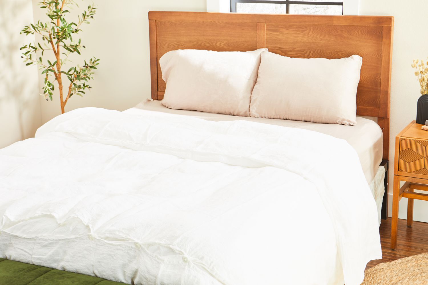 Brooklinen Luxury Sateen Duvet Cover on a bed with a wooden headboard 