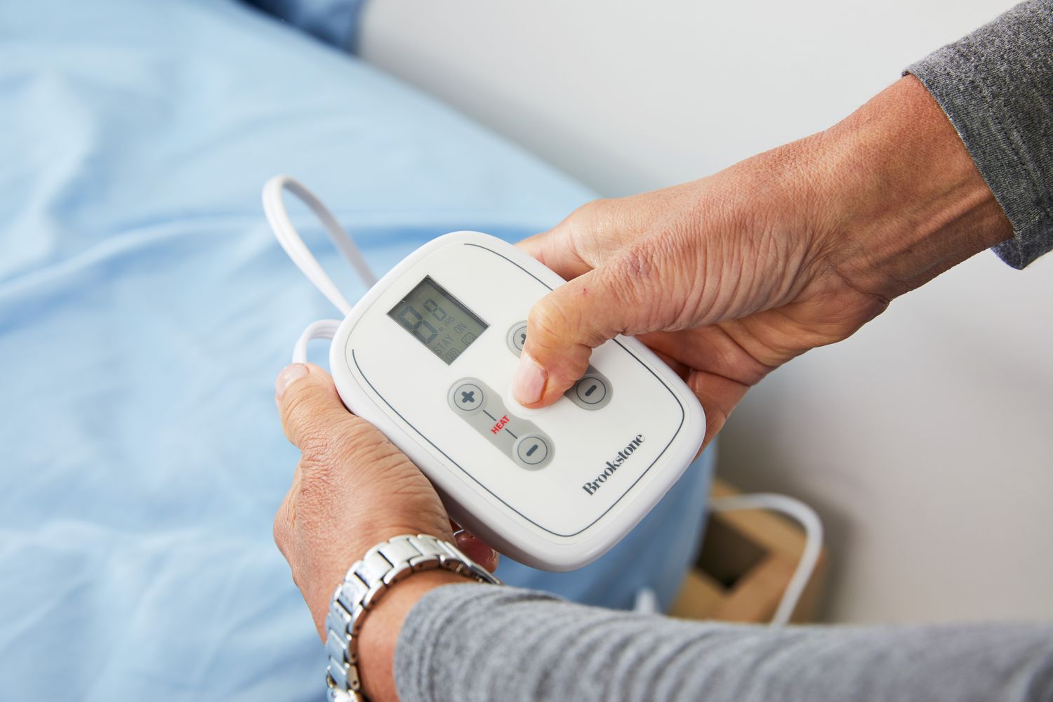 Person pressing button of controller of Brookstone N-A-P Heated Plush Blanket