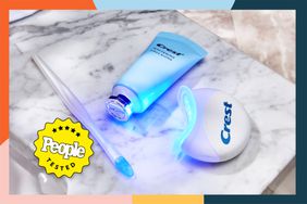 The whitening paste tube, applicator and LED light for the Crest Whitening Emulsions LED Teeth Whitening Kit on a marble counter.