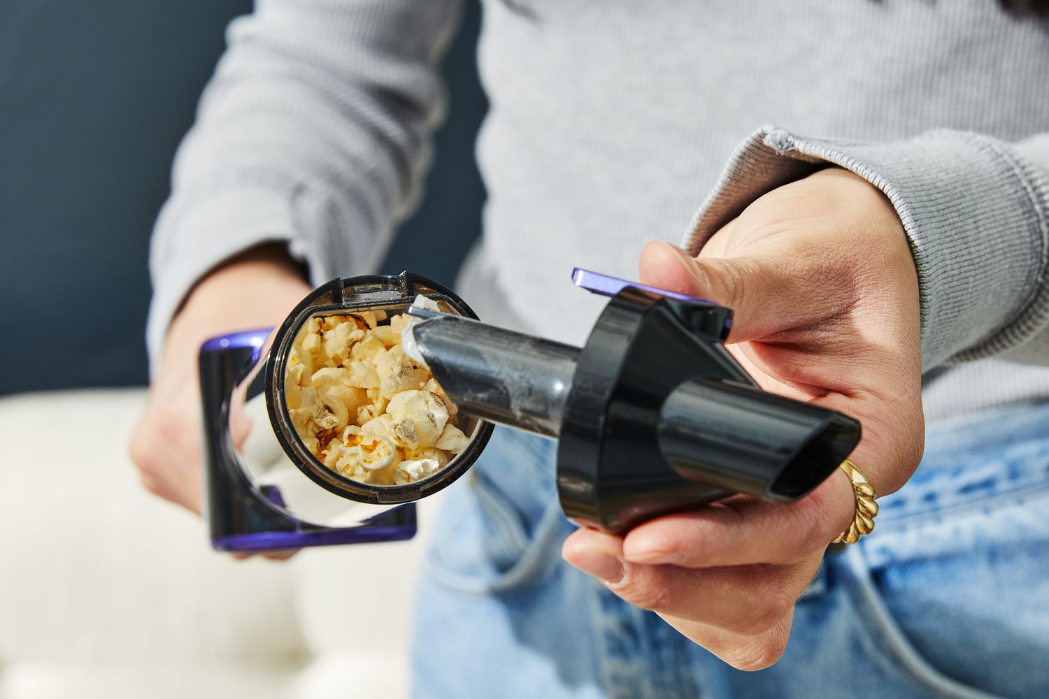 Closeup person emptying Nicebay Handheld Cordless Vacuum dirt-cup with popcorn