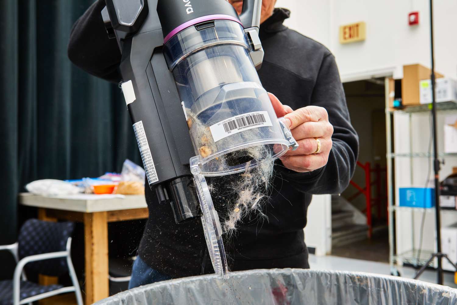 Person emptying the Innova Cordless Stick Multi-Surface Vacuum into a trash bin 