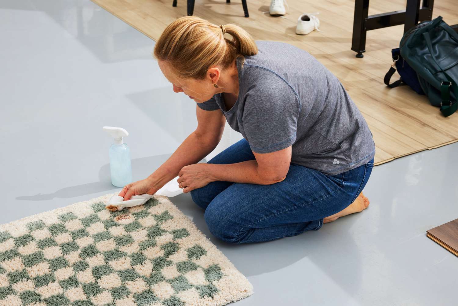 A person cleans a stain off of the AllModern Walker Checkered Shag Area Rug