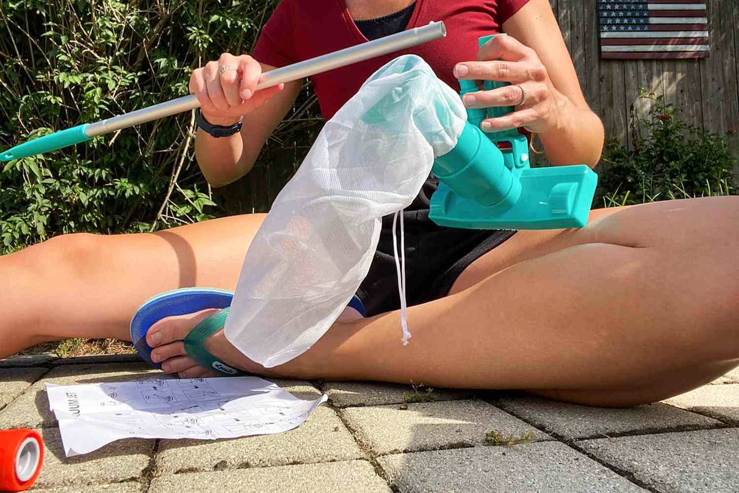 Person sitting on cement assembling Poolwhale Pool & Spa vacuum