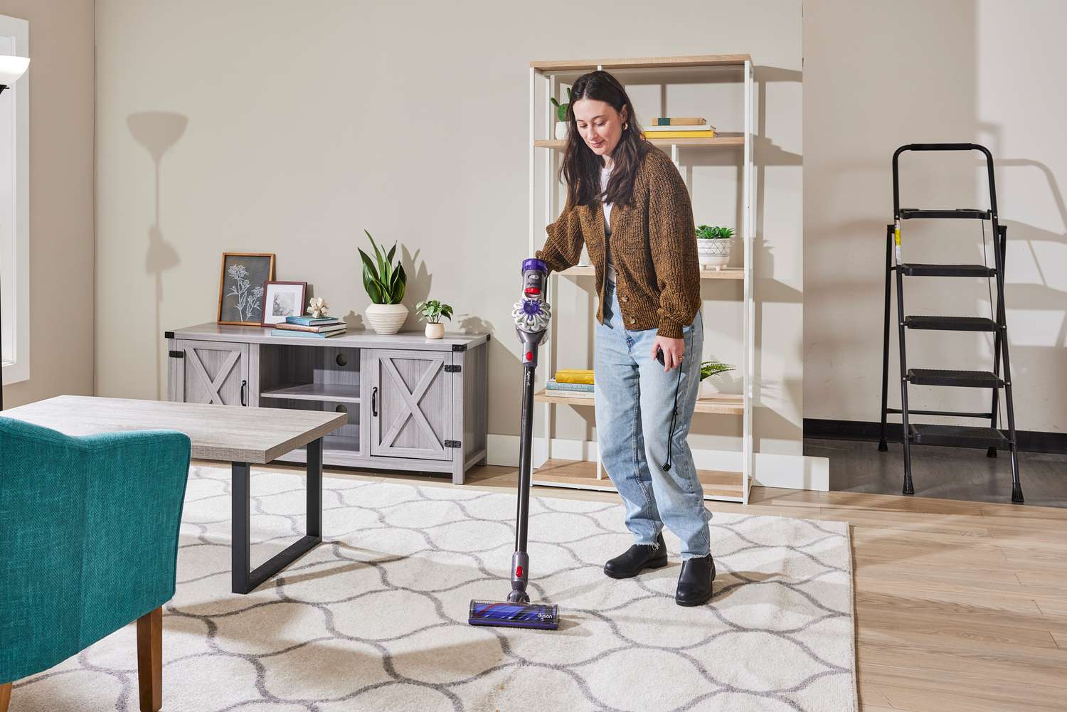 A person using the Dyson V8 on a rug in a living room set