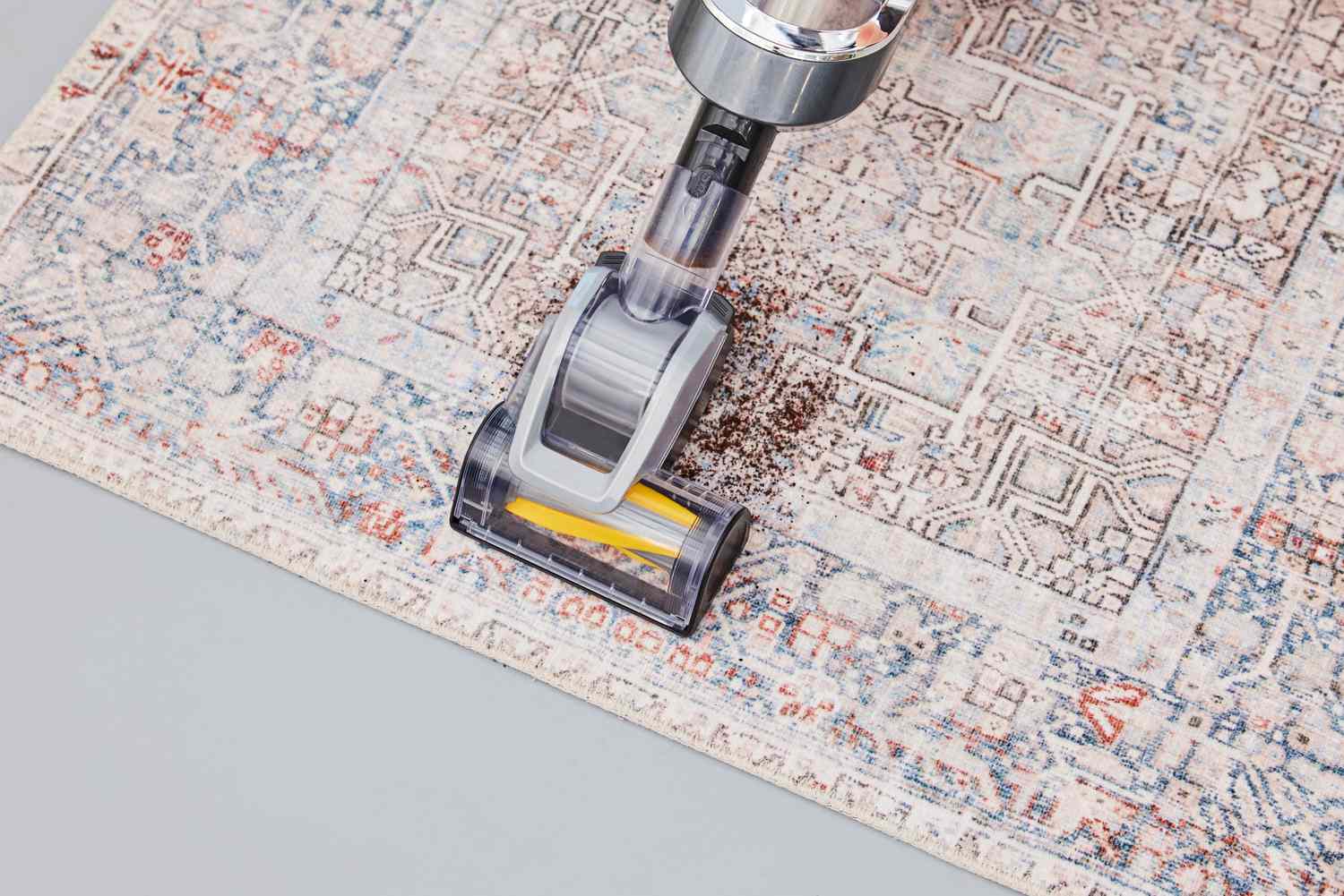 A person vacuums the Chris Loves Julia x Loloi Jules Oriental Area Rug