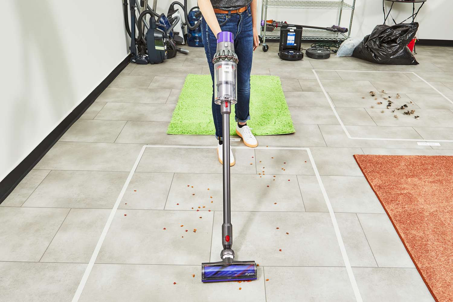 Person using Dyson Cyclone V10 Animal Cordless Stick Vacuum to clean dog food from tile floor