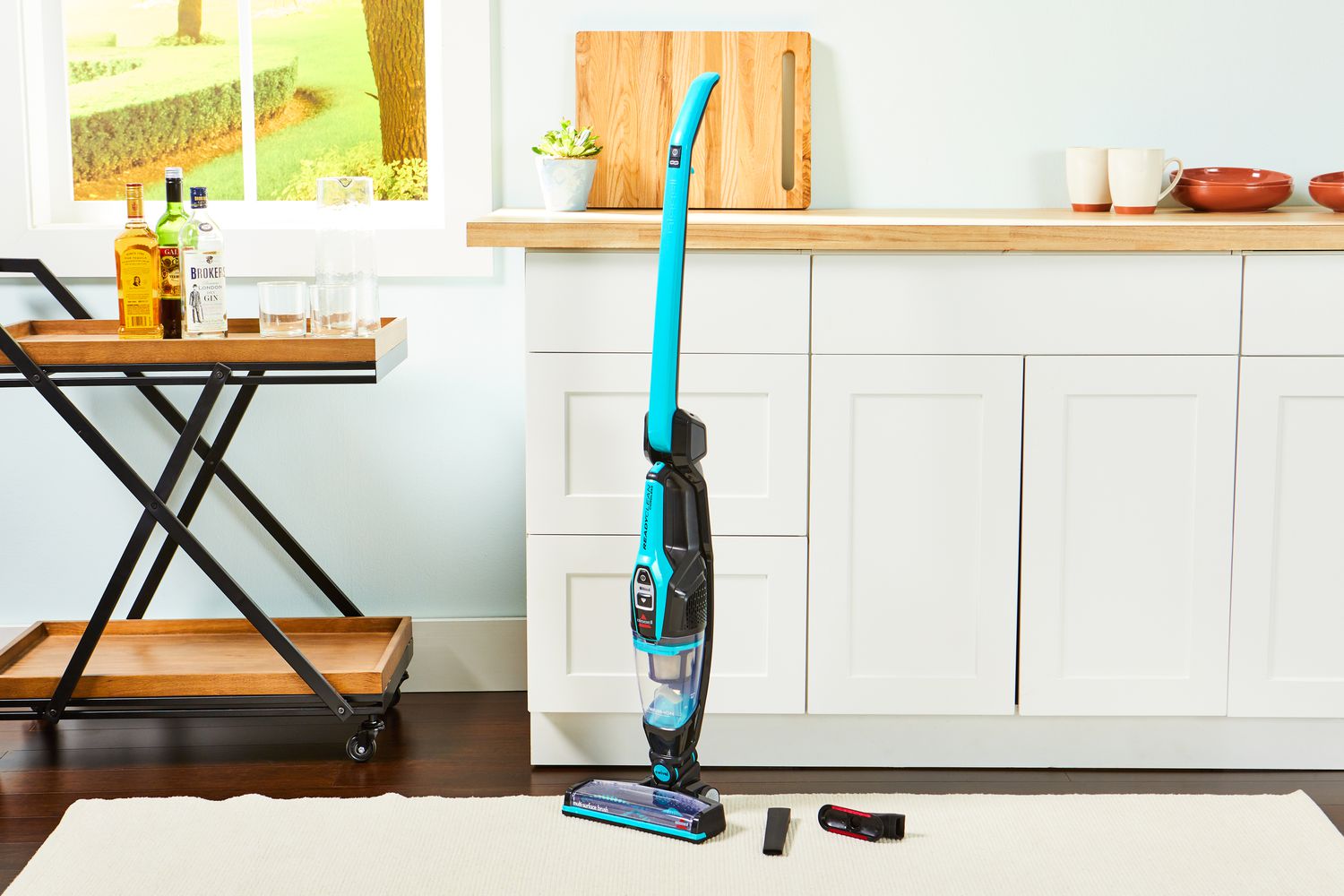 The BISSELL 3061 Featherweight Cordless Stick Vacuum staged in a kitchen on a rug.