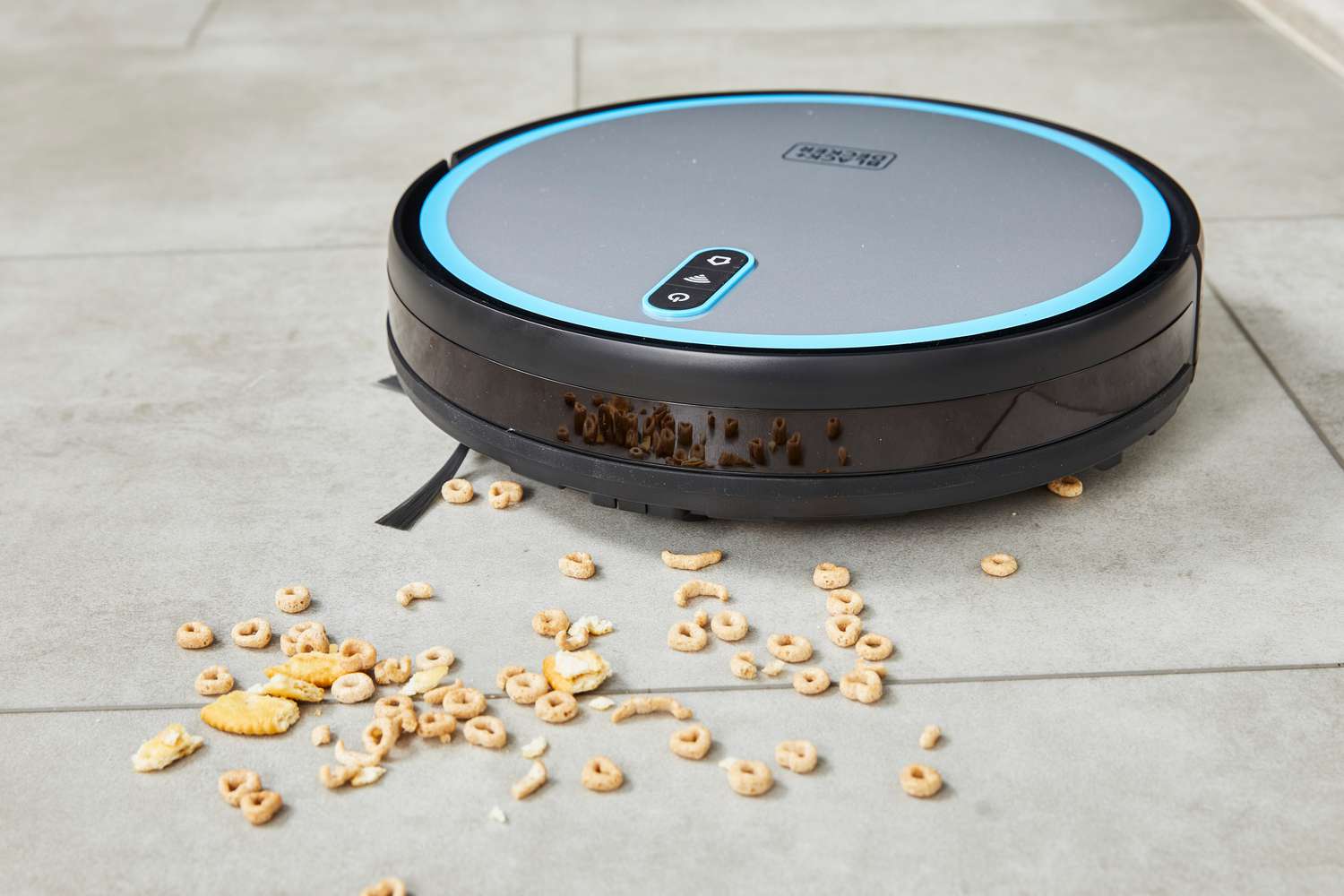 A Black + Decker RoboSeries Robot Vacuum cleans up Cheerios and crackers from a tile floor