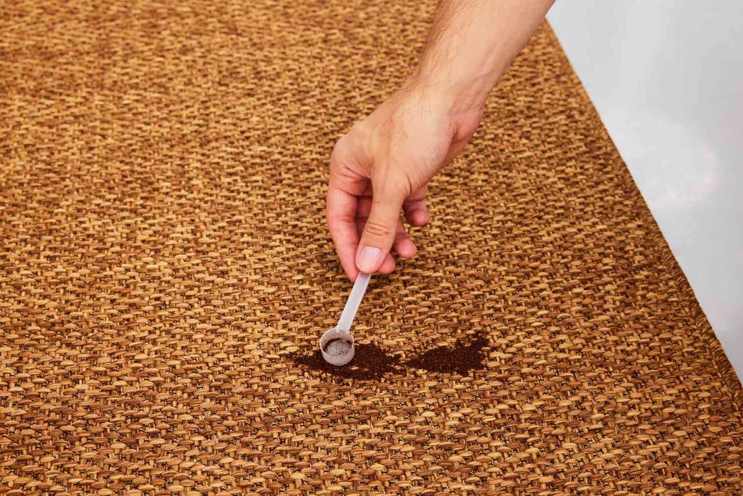 A person pours coffee grounds onto the IKEA LYDERSHOLM Rug