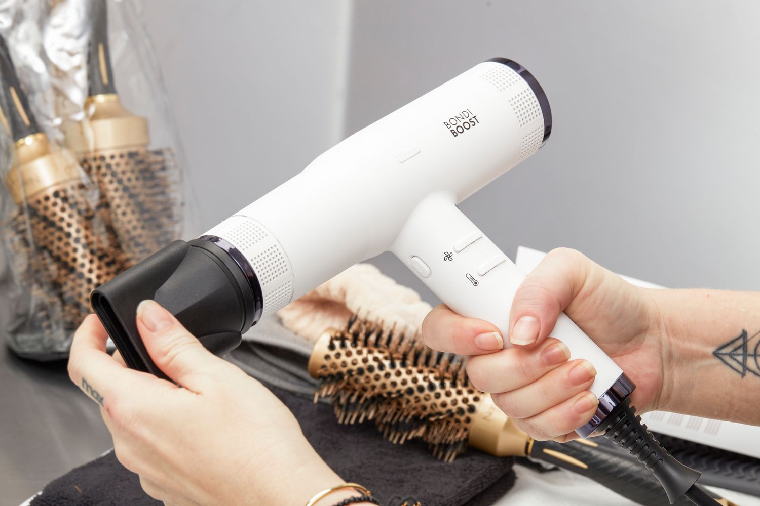 hands putting attachment onto BondiBoost Sonic Hair Dryer