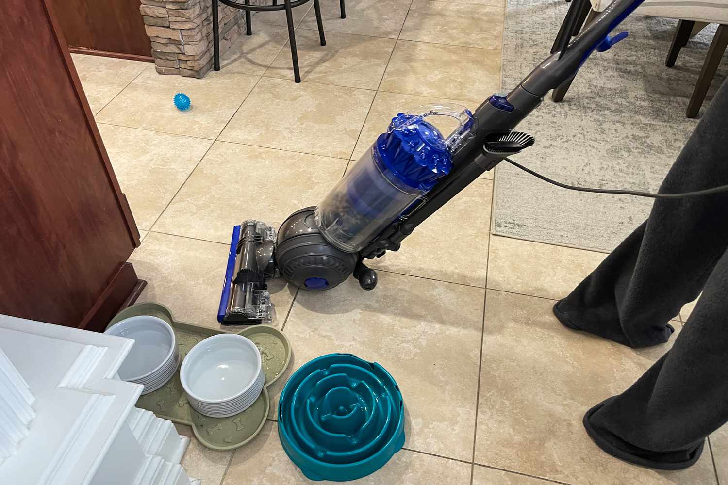 A person uses the Dyson Ball Animal Total Clean to clean a tile floor