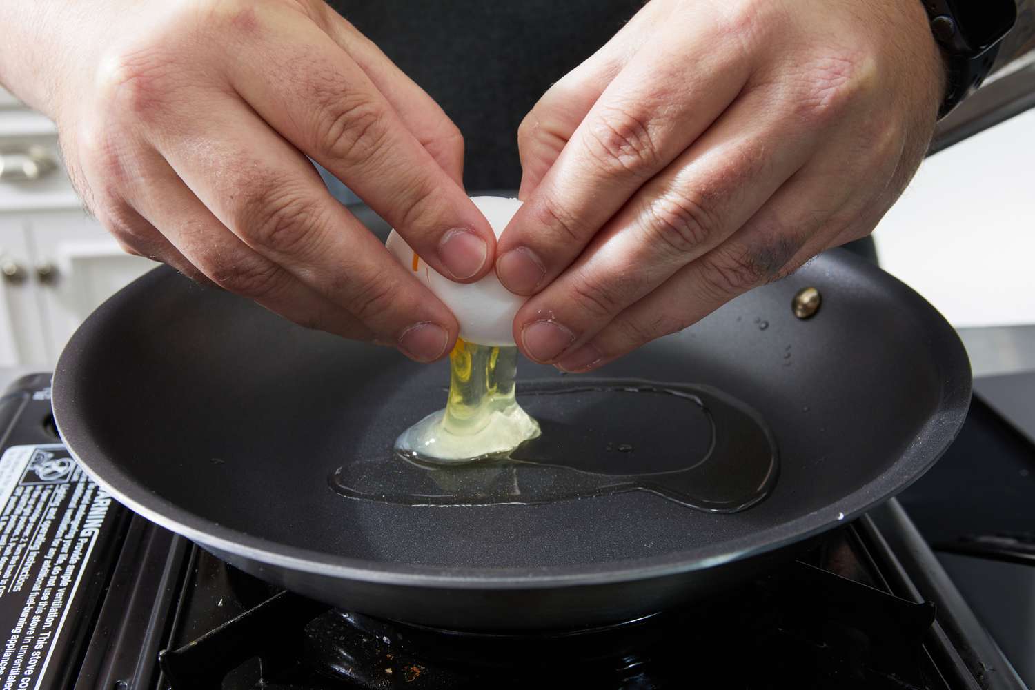 Hands cracking egg into a Made In nonstick sauté pan