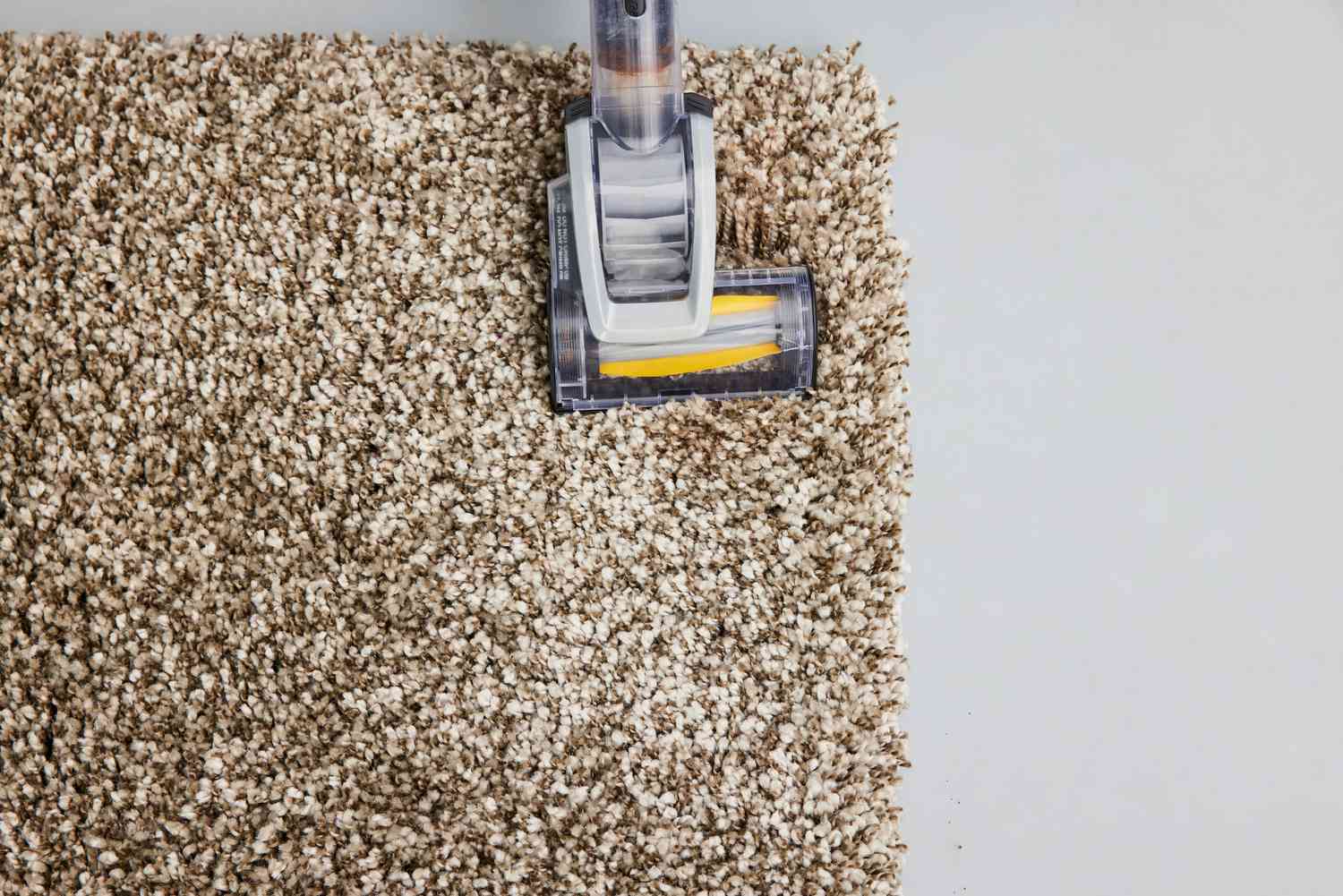 A person vacuums the Safavieh Milan Shag Collection Accent Rug