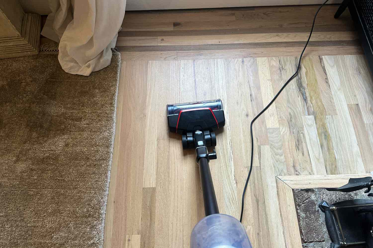 A person cleans a hardwood floor using the Bissell CleanView Pet Slim Corded Stick Vacuum