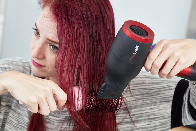 person using brush and Chi Lava Hair Dryer to dry hair