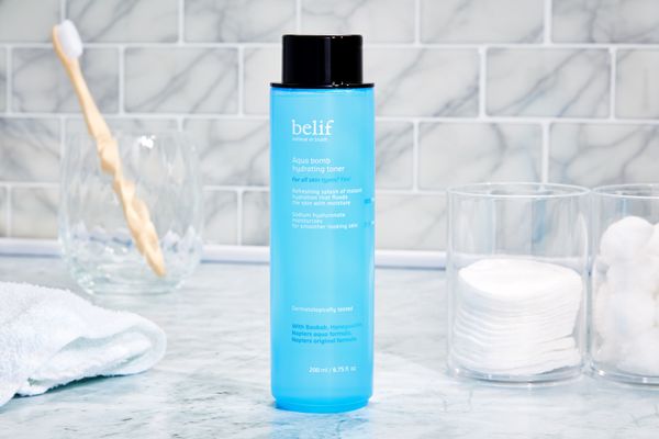 Belif Aqua Bomb Hydrating Toner bottle on a marble counter next to cotton rounds 