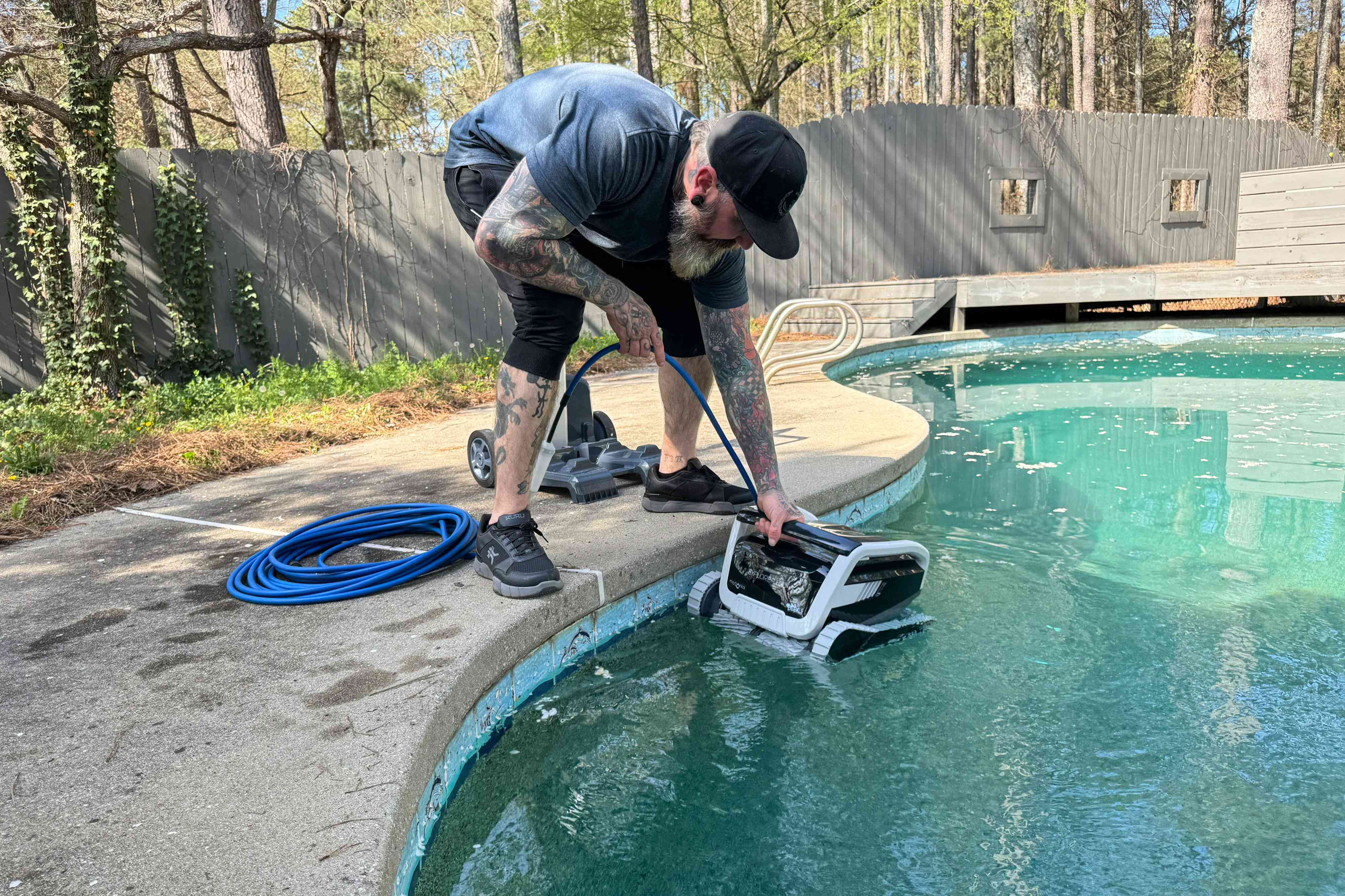 A person places the Dolphin Explorer E70 Pool Cleaner into a pool