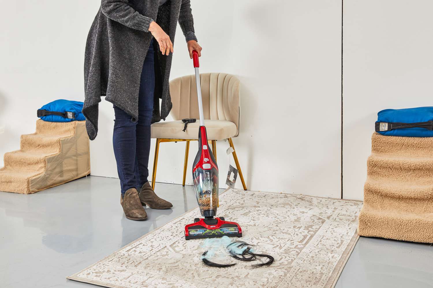 Person vacuuming fuzz and hair from a rug using the DirtDevil Versa Cordless 3-in-1 Stick Vacuum