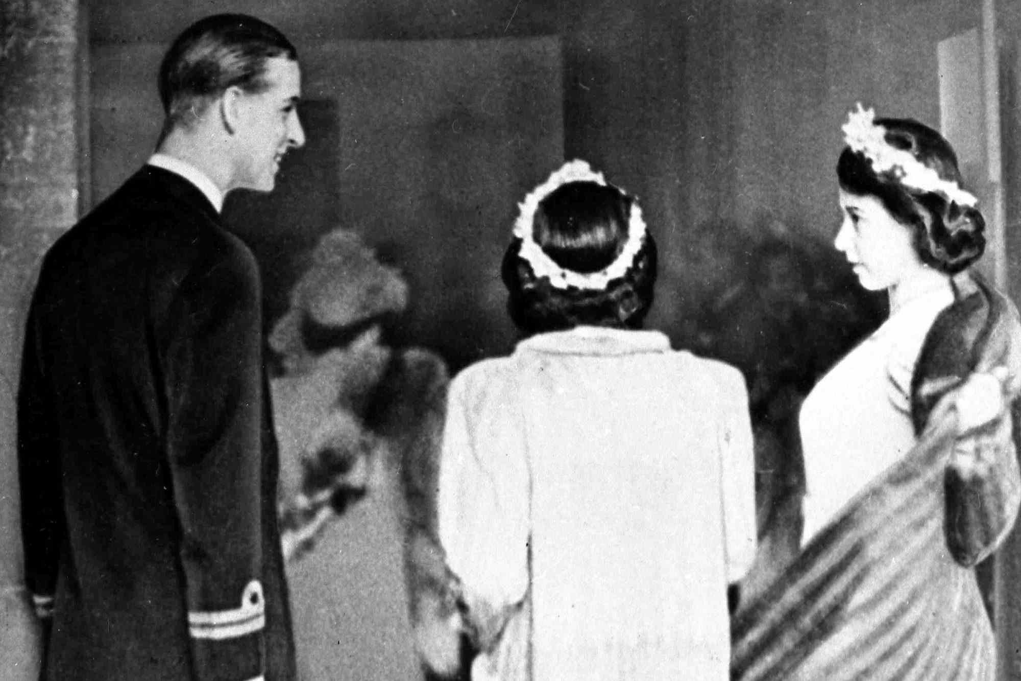 Prince Philip of Greece, later the Duke of Edinburgh, acts as an usher, assisting Princess Elizabeth