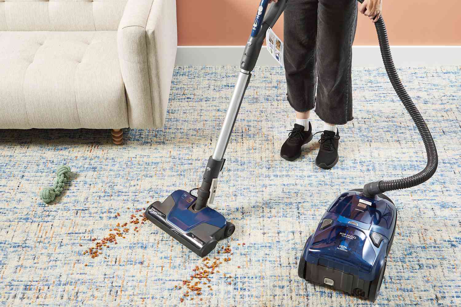 A person using the Kenmore Pet Friendly Pop-N-Go Canister Vacuum on a blue and yellow carpet