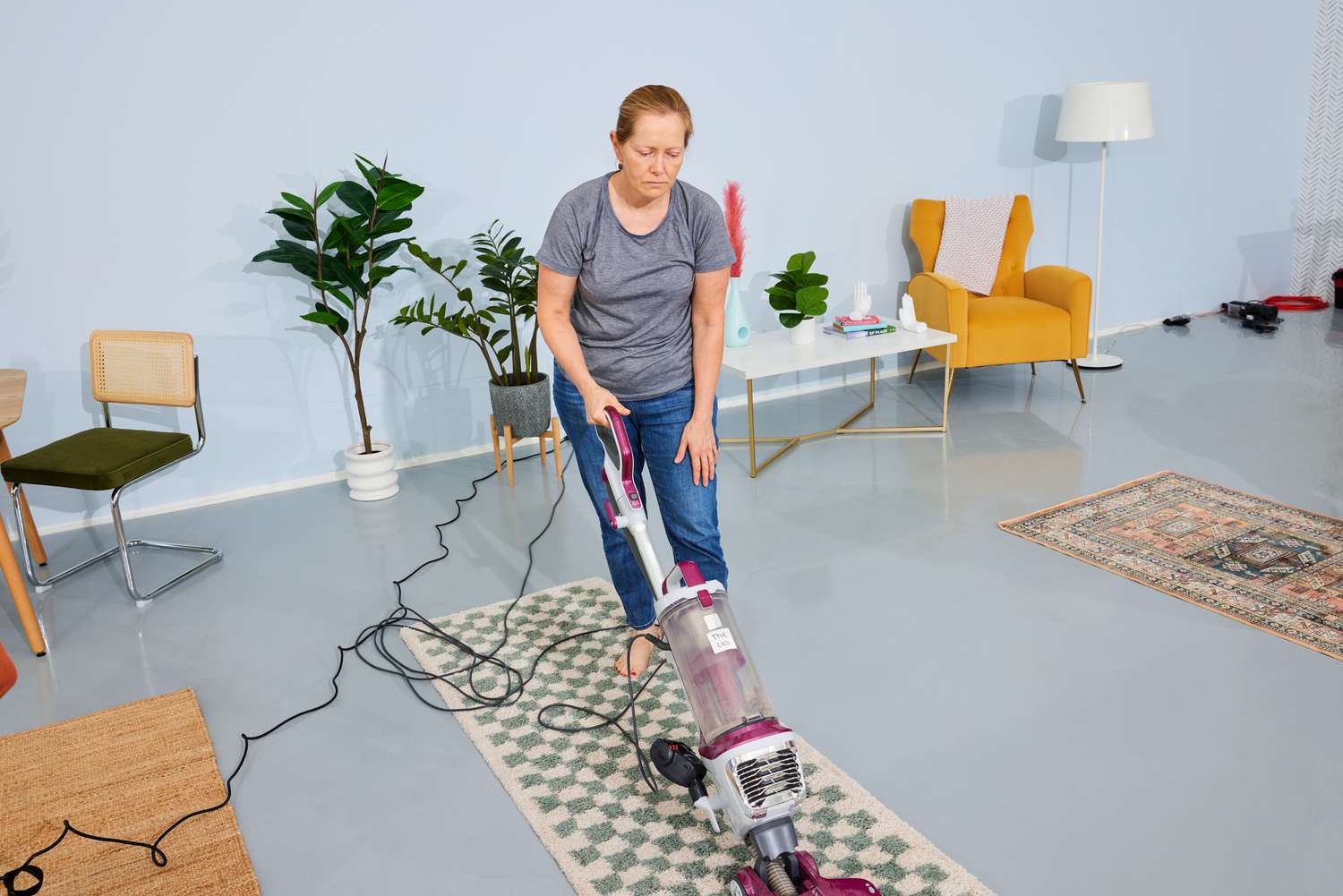 A person vacuums the AllModern Walker Checkered Shag Area Rug