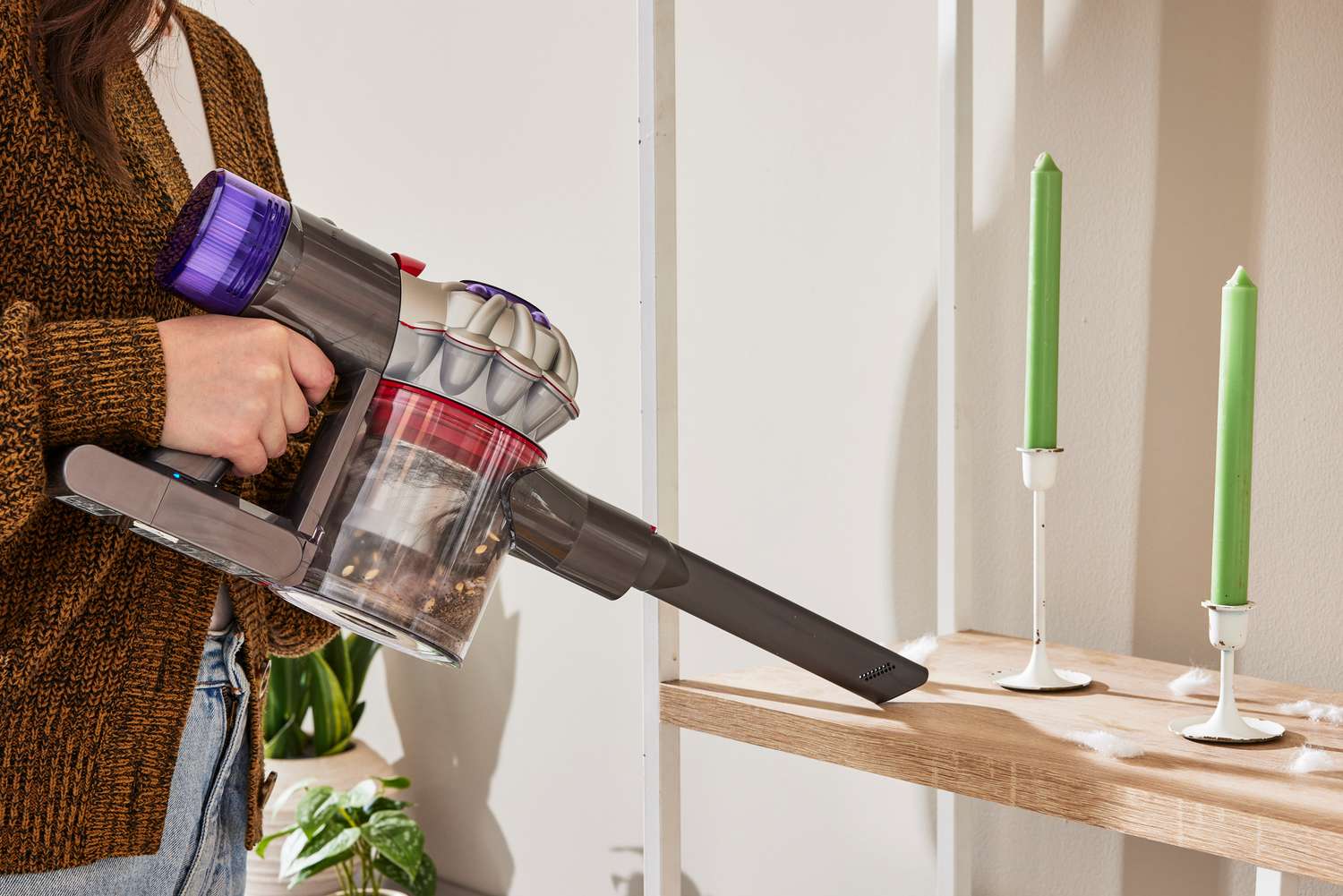 A person using the hand held part of the Dyson V8 on a shelf