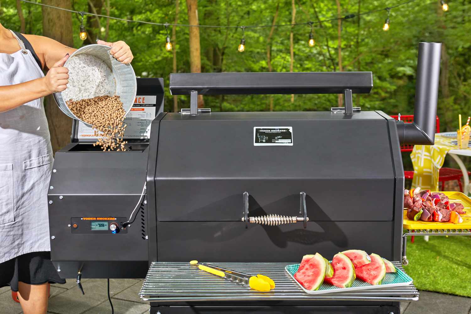 Person pouring a bucket of pellets into the Yoder Smokers YS640S Pellet Grill