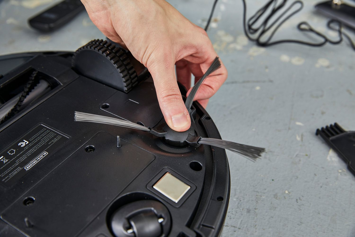 A person adjusts the Black + Decker RoboSeries Robot Vacuum 