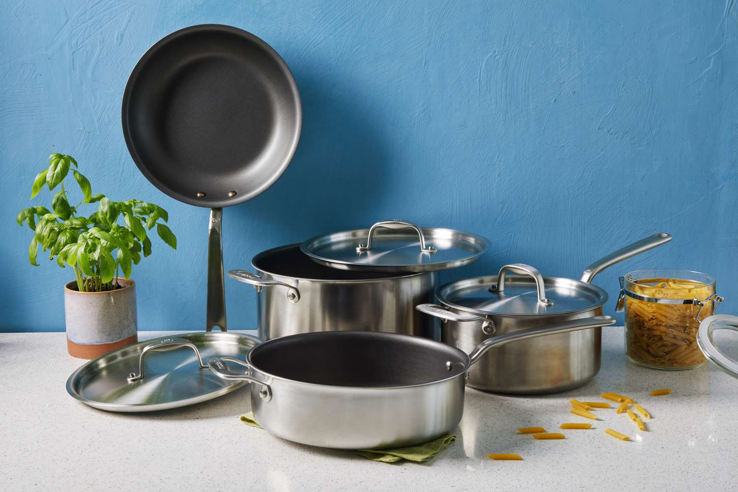 Made In 7-Piece The Non Stick Set displayed on countertop with basil plant and container of dry pasta