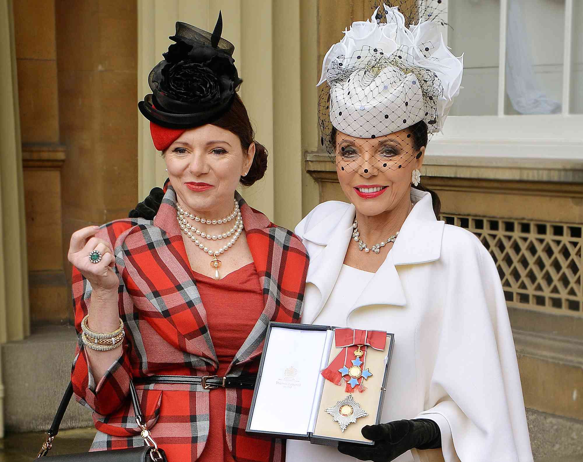 Joan Collins (L) poses for pictures with her daughter Tara Newley as she holds her insignia of Commander of the Order of the British Empire, (CBE) after it was awarded to her by Prince Charles at an Investiture Ceremony at Buckingham Palace in central London on March 26, 2015