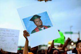  A demonstrator carries a picture of Michael Brown during a protest along Florissant Avenue on August 16, 2014