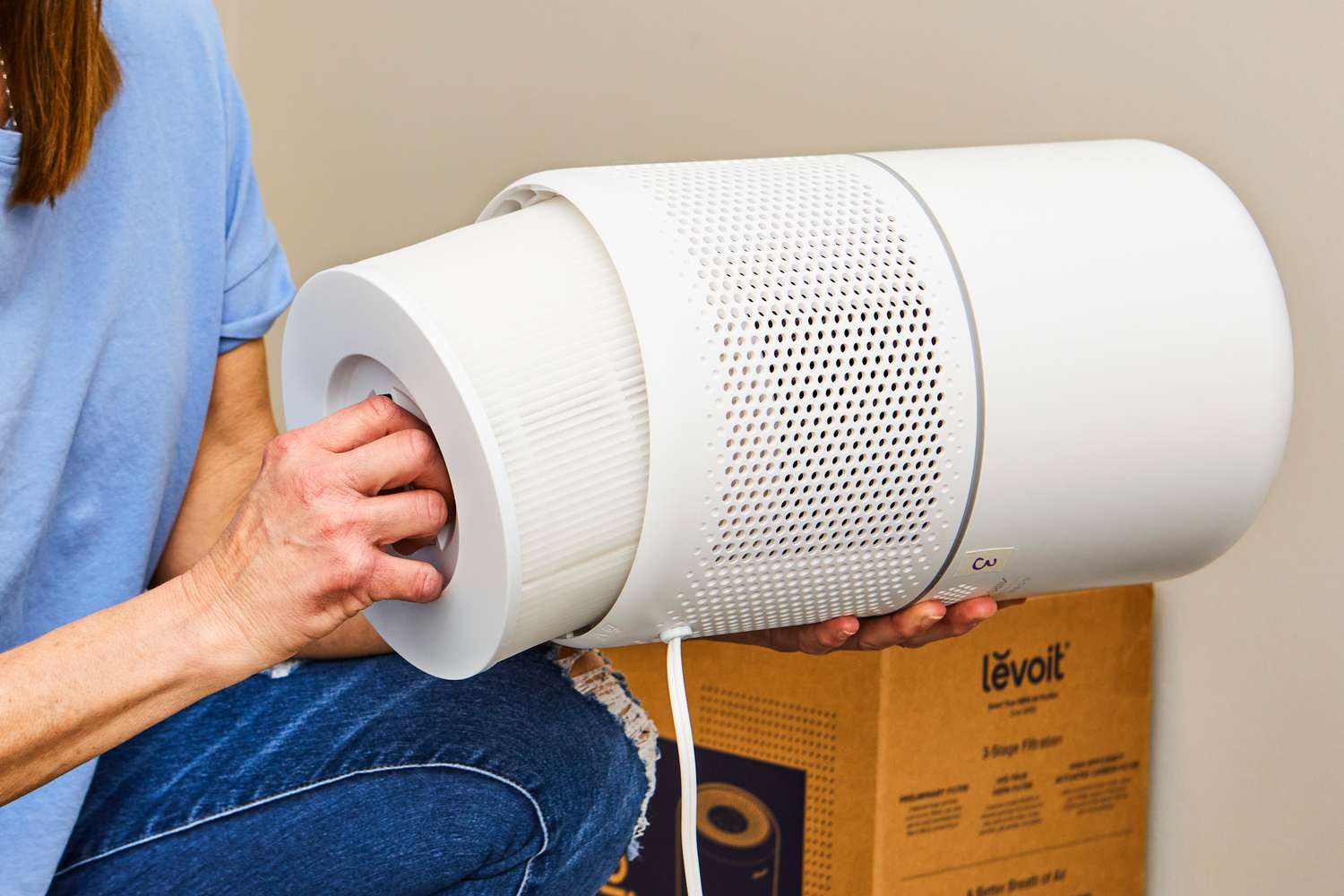 A hand deconstructing the Levoit Core 300S Smart True HEPA Air Purifier