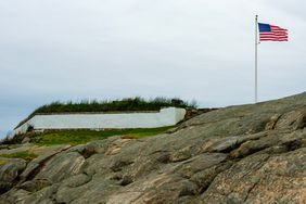 American flag waving over the rocks at Fort Taber Park in New Bedford, Massachusetts, USA