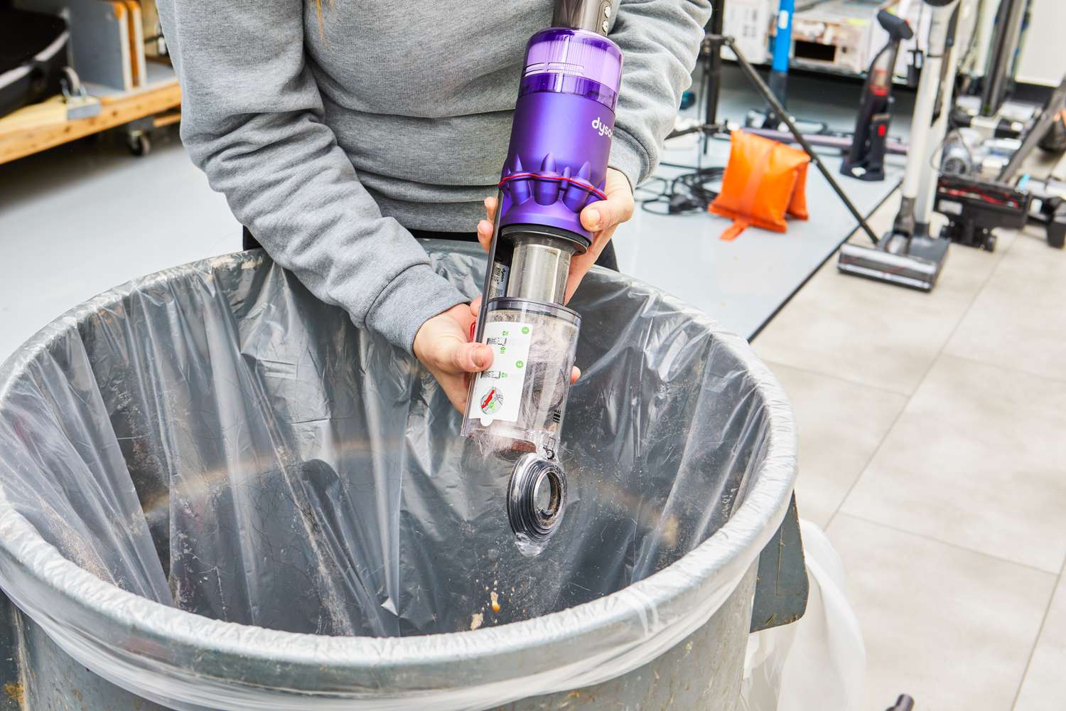 Person emptying the Dyson Omni-Glide+ Cordless Vacuum dustbin into the trash
