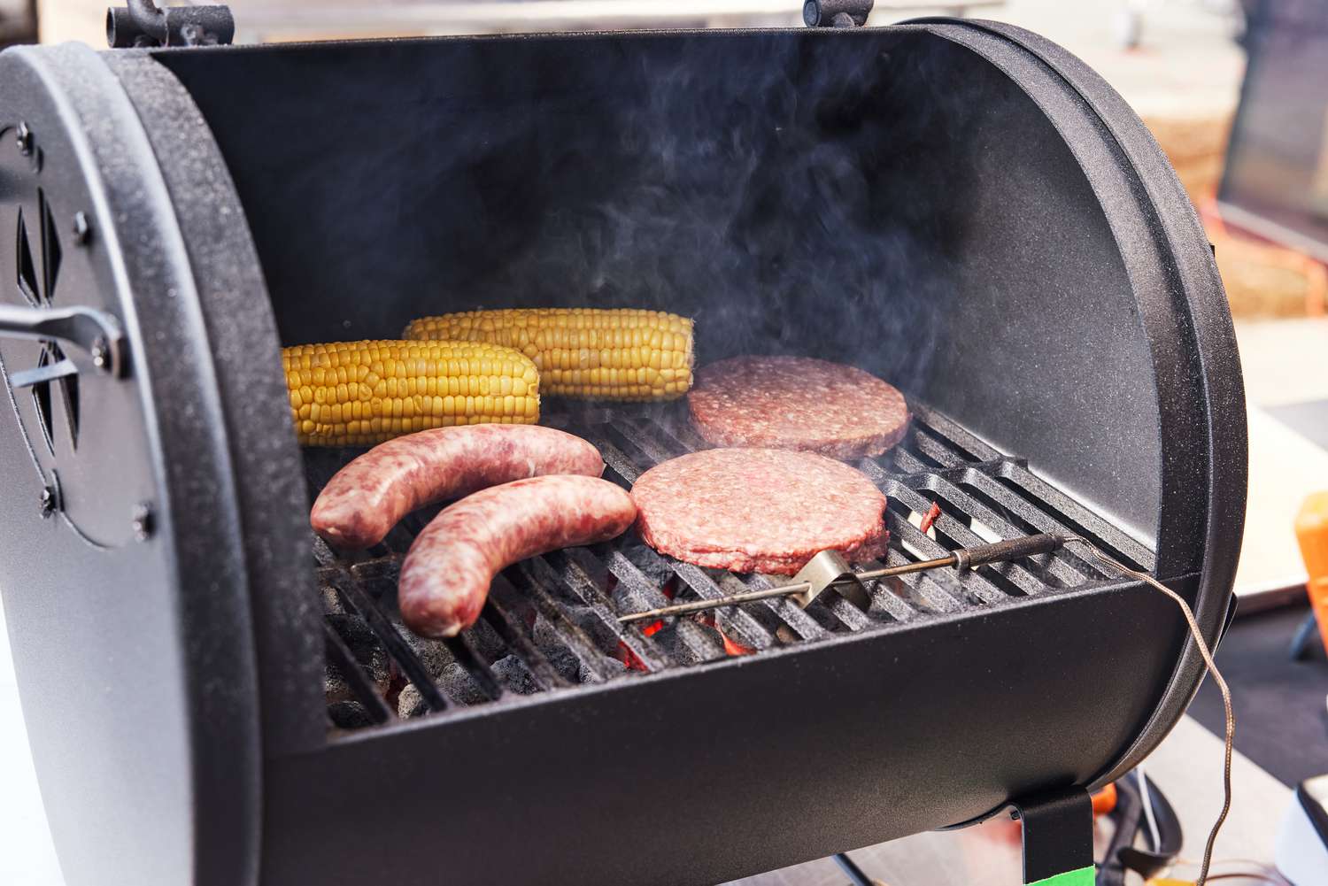 burgers, sausage, and corn cooking on Char-Griller Portable Charcoal Grill and Side Firebox 