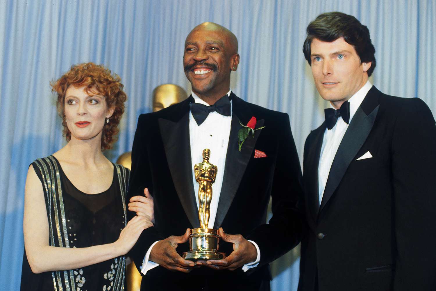 Actress Susan Sarandon (left) and Actor Christopher Reeves flank either side of Louis Gossett Jr., winner of the 1982 Academy Award for Best Supporting Actor for his role in An Officer and a Gentleman backstage during the Academy Awards Ceremony.