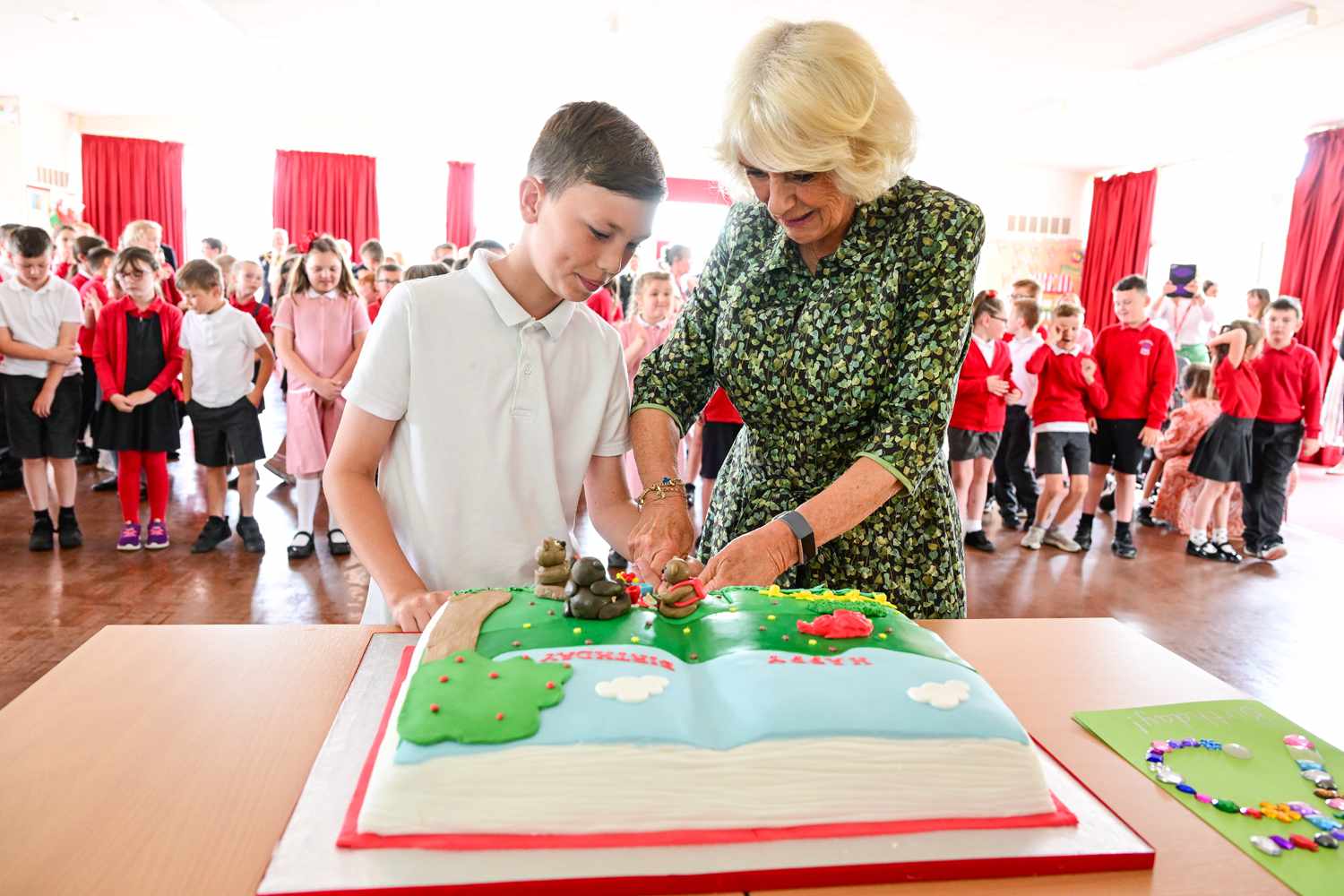 Camilla, Duchess of Cornwall cuts a birthday cake presented to her during her visit to Millbrook Primary School on July 06, 2022 in Newport, Wales