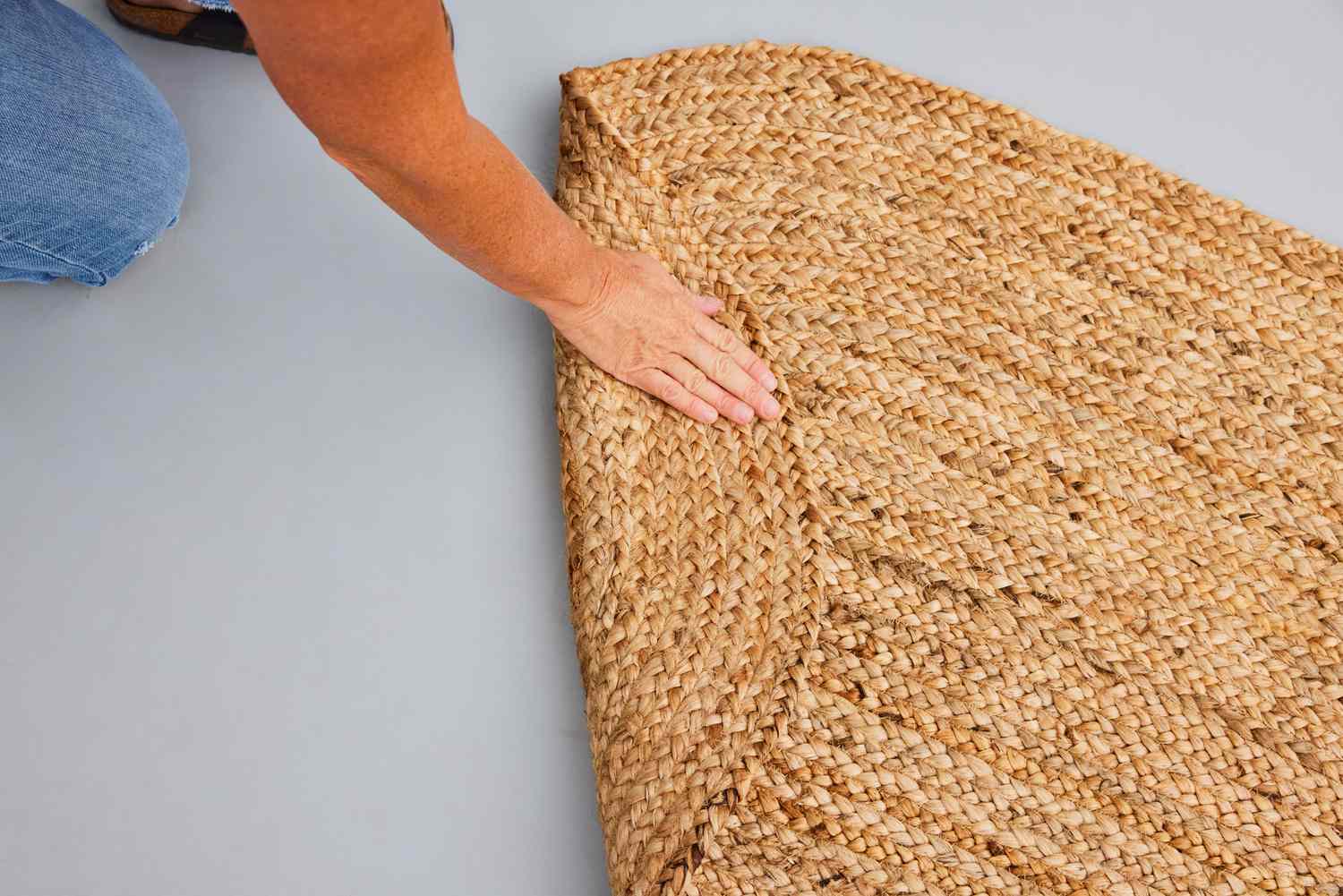 A person folds over the nuLOOM Rigo Hand Woven Jute Area Rug