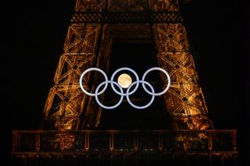 The moon rises behind the Olympic rings displayed on the Eiffel Tower in Paris on July 22, 2024, ahead of the Paris 2024