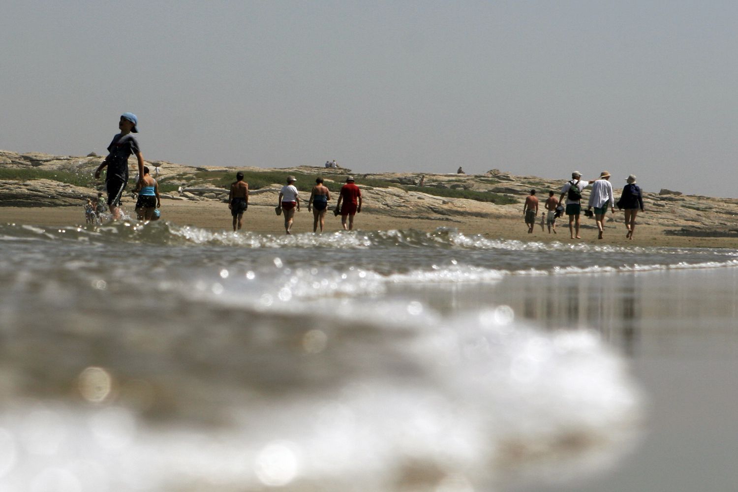 Beachgoers enjoy the walk at low tide out to Fox Island off of Popham Beach State Park in Phippsburg, Maine, June 26, 2007