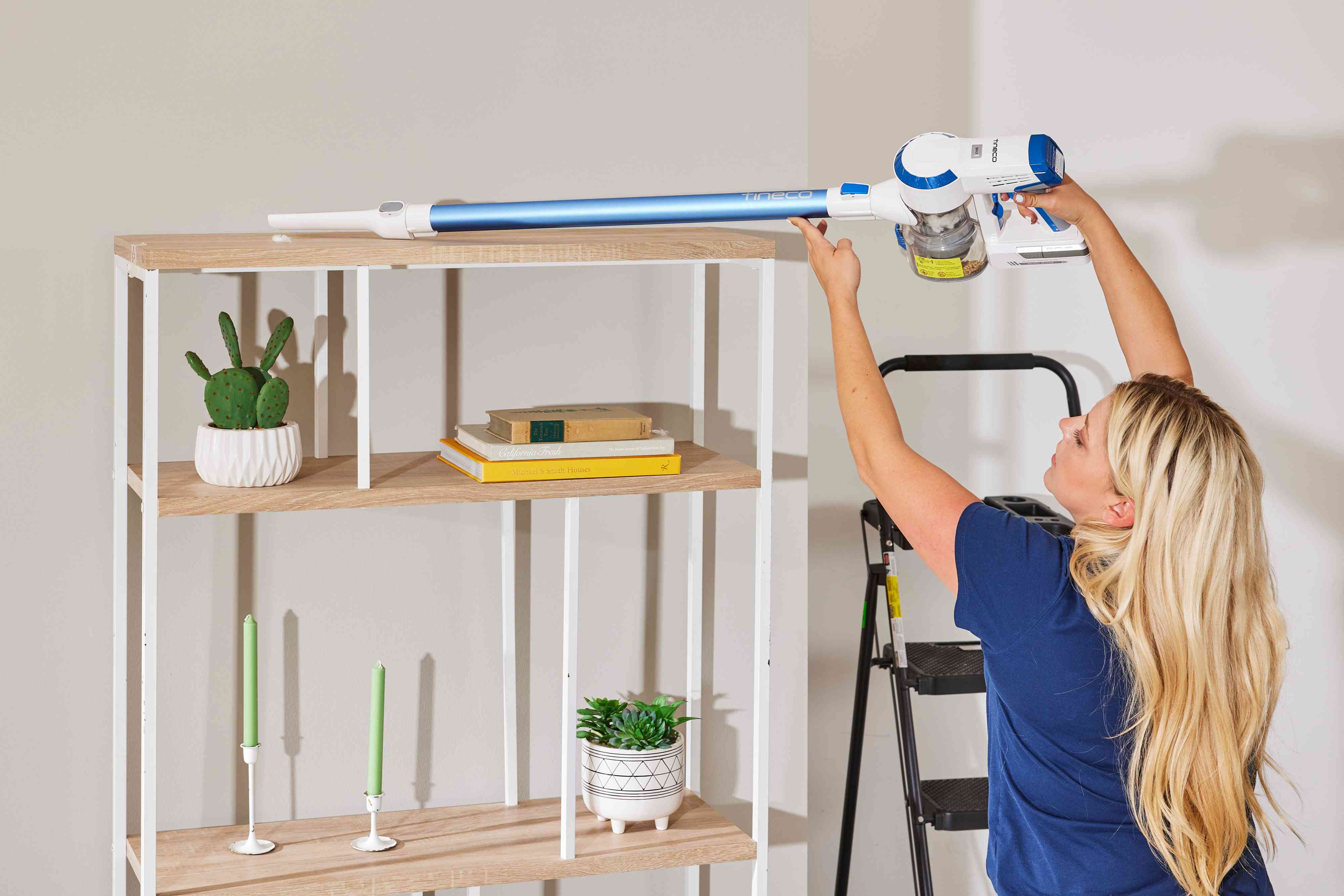 A person using the Tineco A10 Hero Cordless Stick/Handheld Vacuum to clean the top shelf