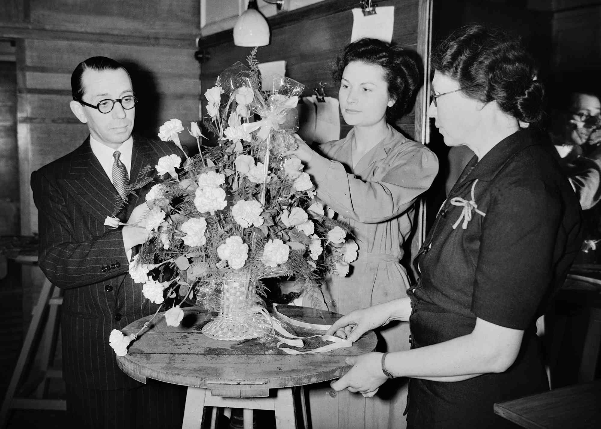 Florist Martin Longman, of Fenchurch Street, who has been appointed to make Princess Elizabeth's bouquet for her wedding to Prince Philip, at work with his assistants Mary Nelson and Constance Fears, 5th November 1947. He is keeping the design a secret until the day of the wedding