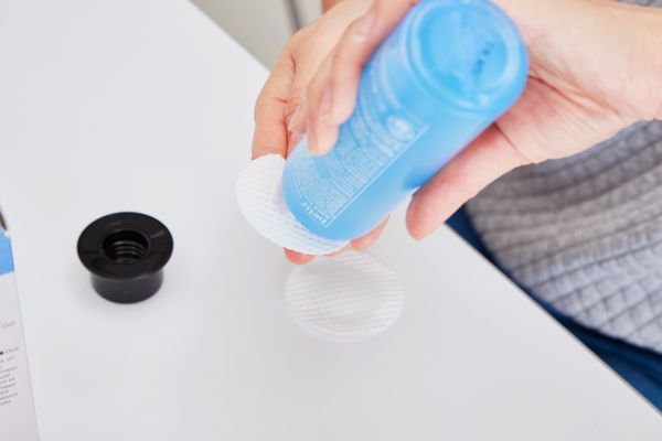 Person pouring Belif Aqua Bomb Hydrating Toner on a cotton round 