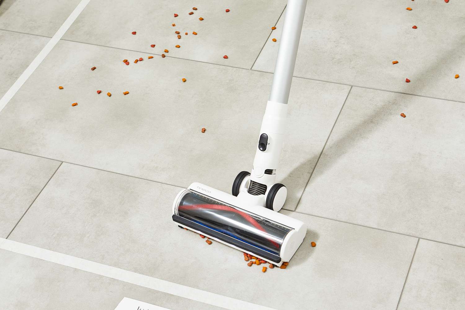 Tineco Pure One S11 Smart Stick/Handheld Vacuum sweeping up food on tiled white floor