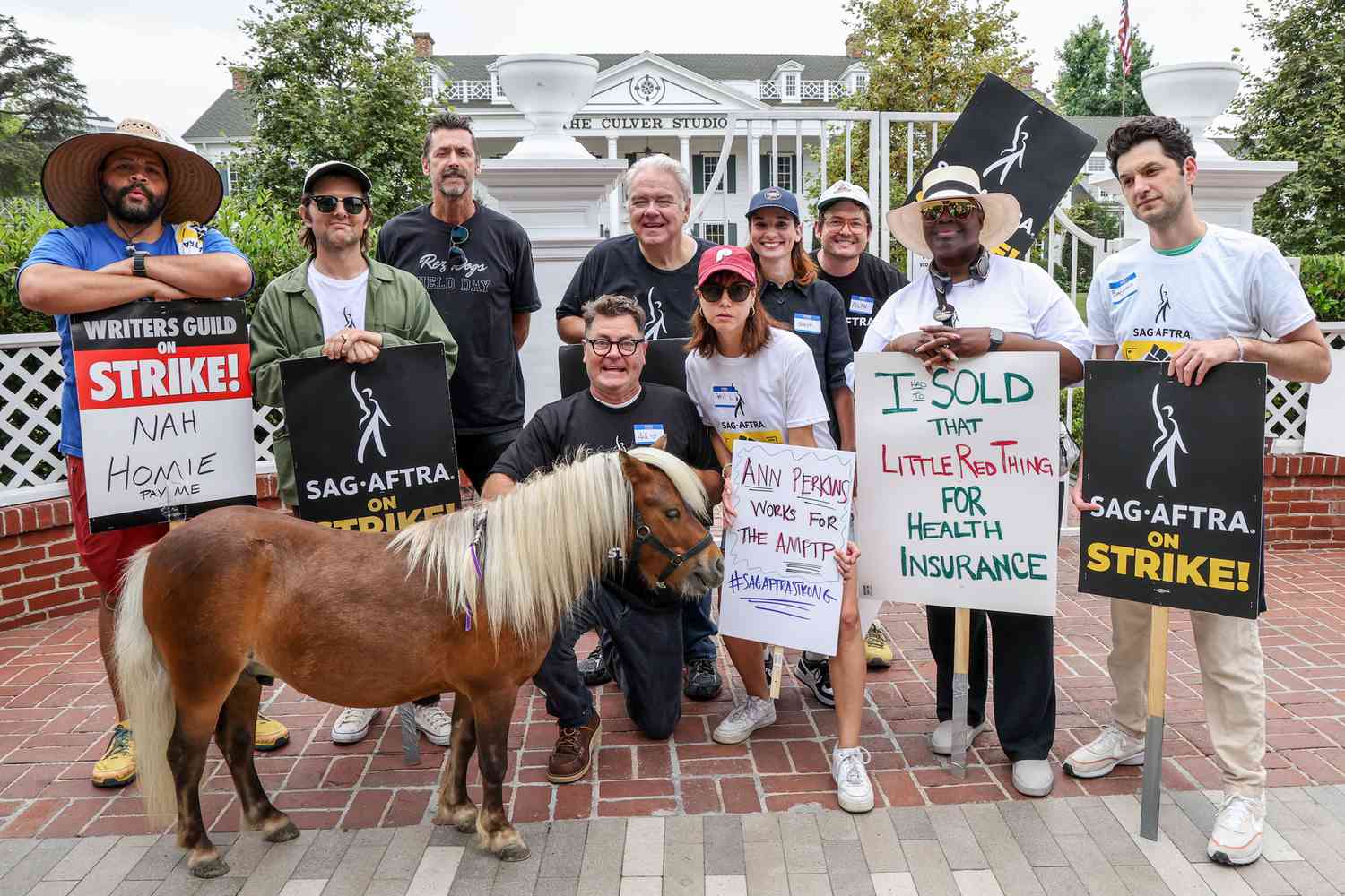 (L-R) Adam Scott, Nick Offerman, Jim O'Heir, Aubrey Plaza, Retta and Ben Schwartz, alongside members of SAG-AFTRA and their supporters, pose for a photograph while picketing