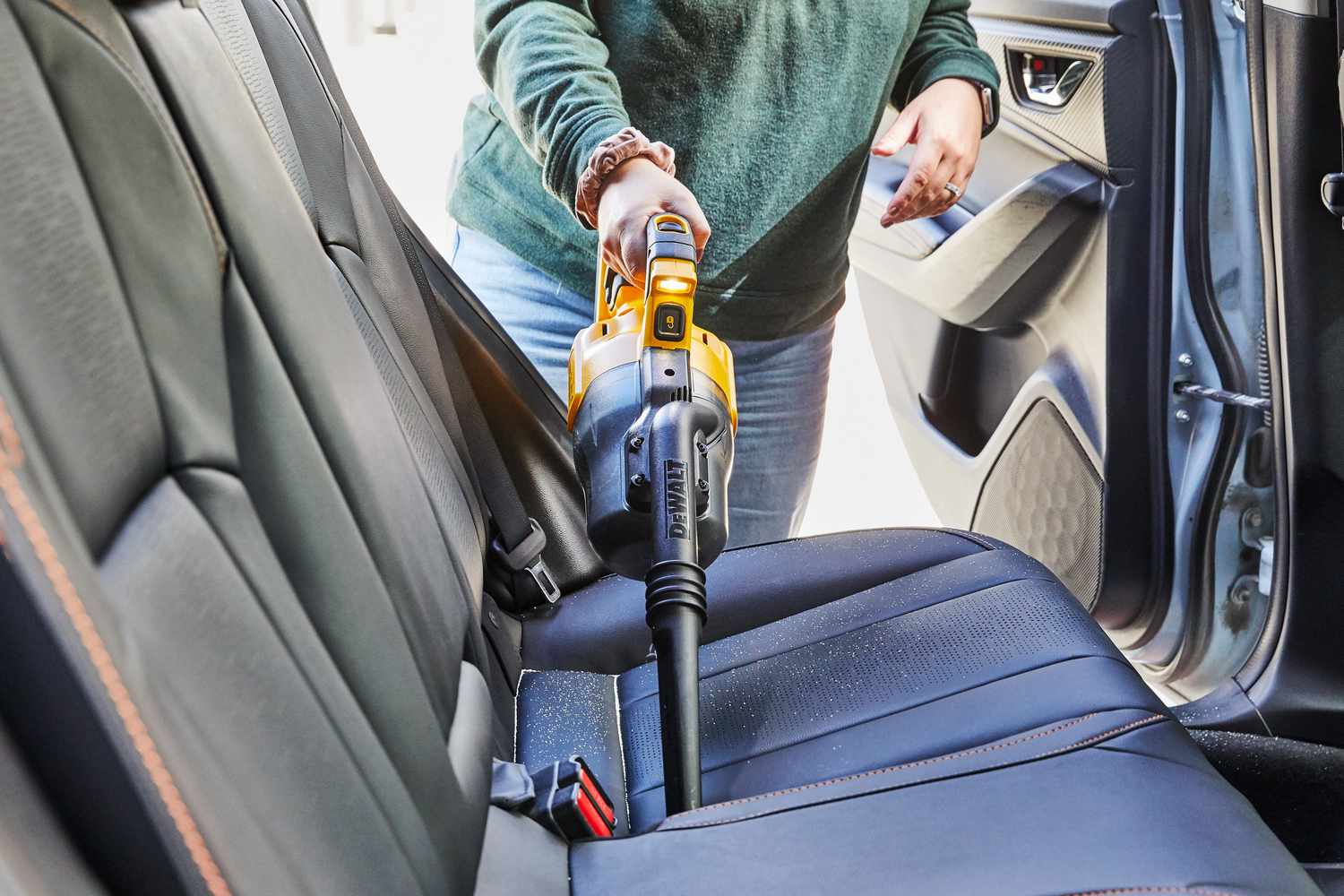 Person using Dewalt 20-Volt Cordless Handheld Vacuum to clean car seat