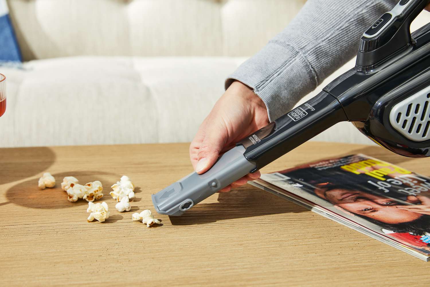 Person using Black+Decker Dustbuster AdvancedClean+ Cordless Hand Vacuum to clean popcorn from coffee table