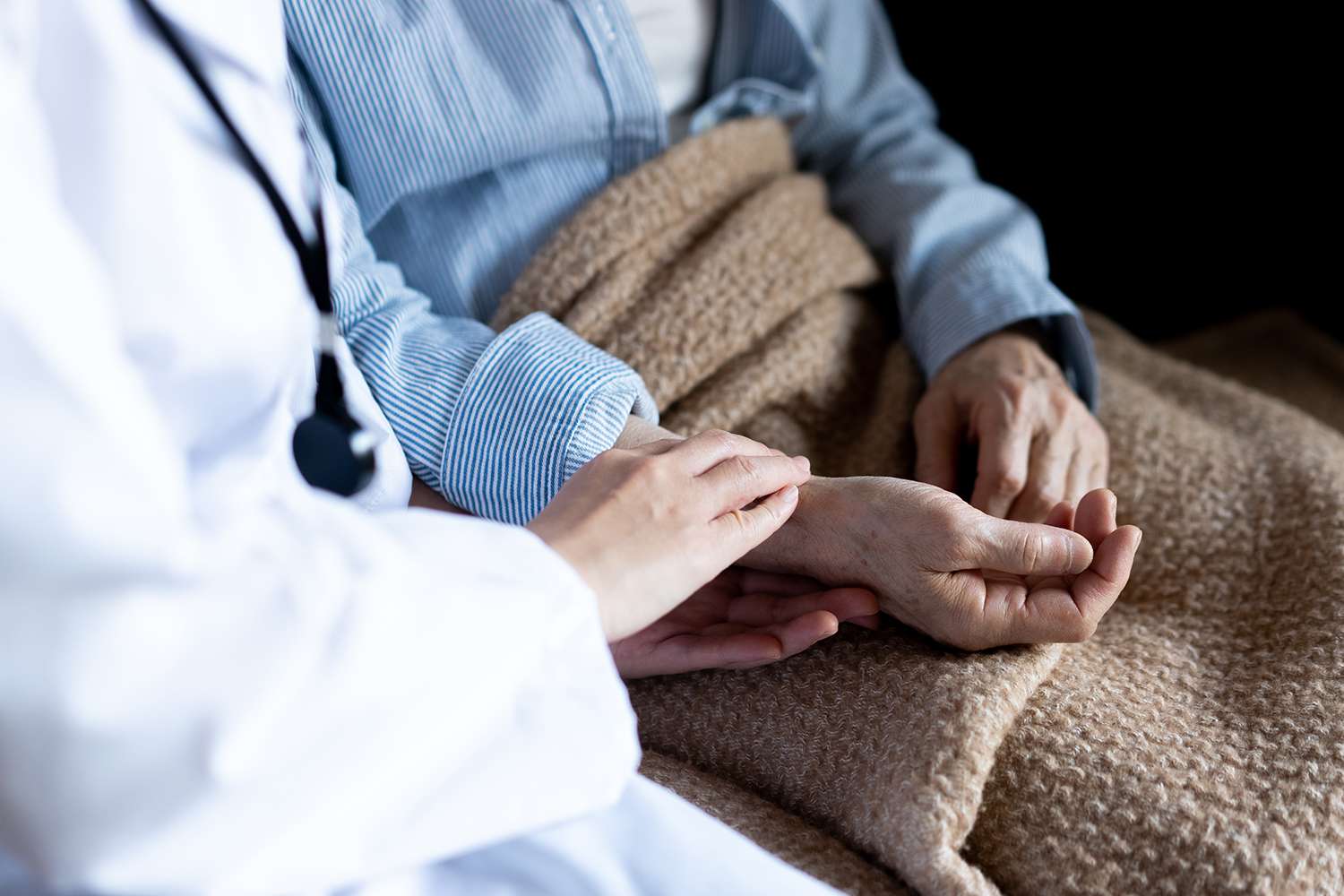 An elderly woman's hand being held by a doctor