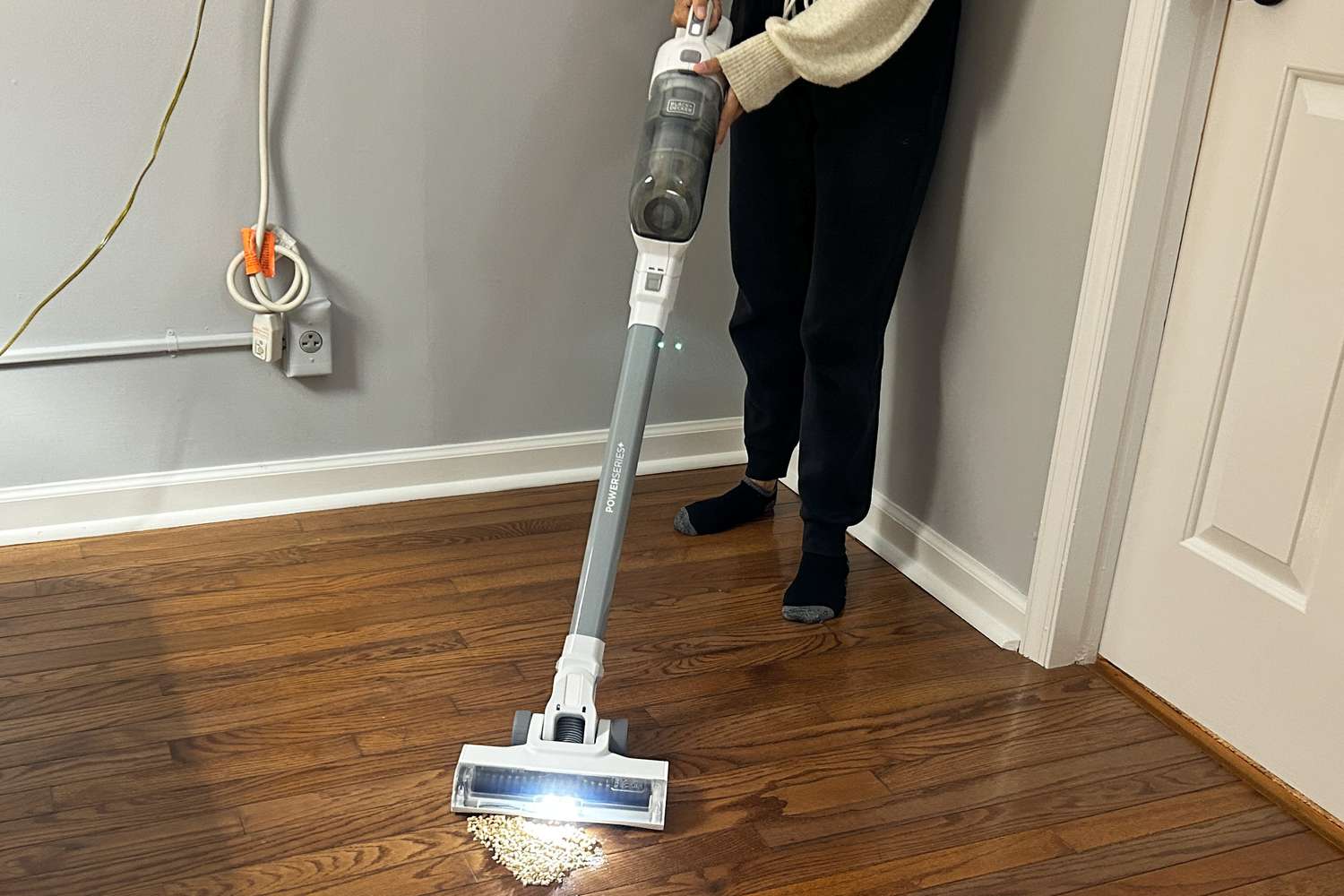 A person uses the Black + Decker Powerseries Option 2 on a wooden floor