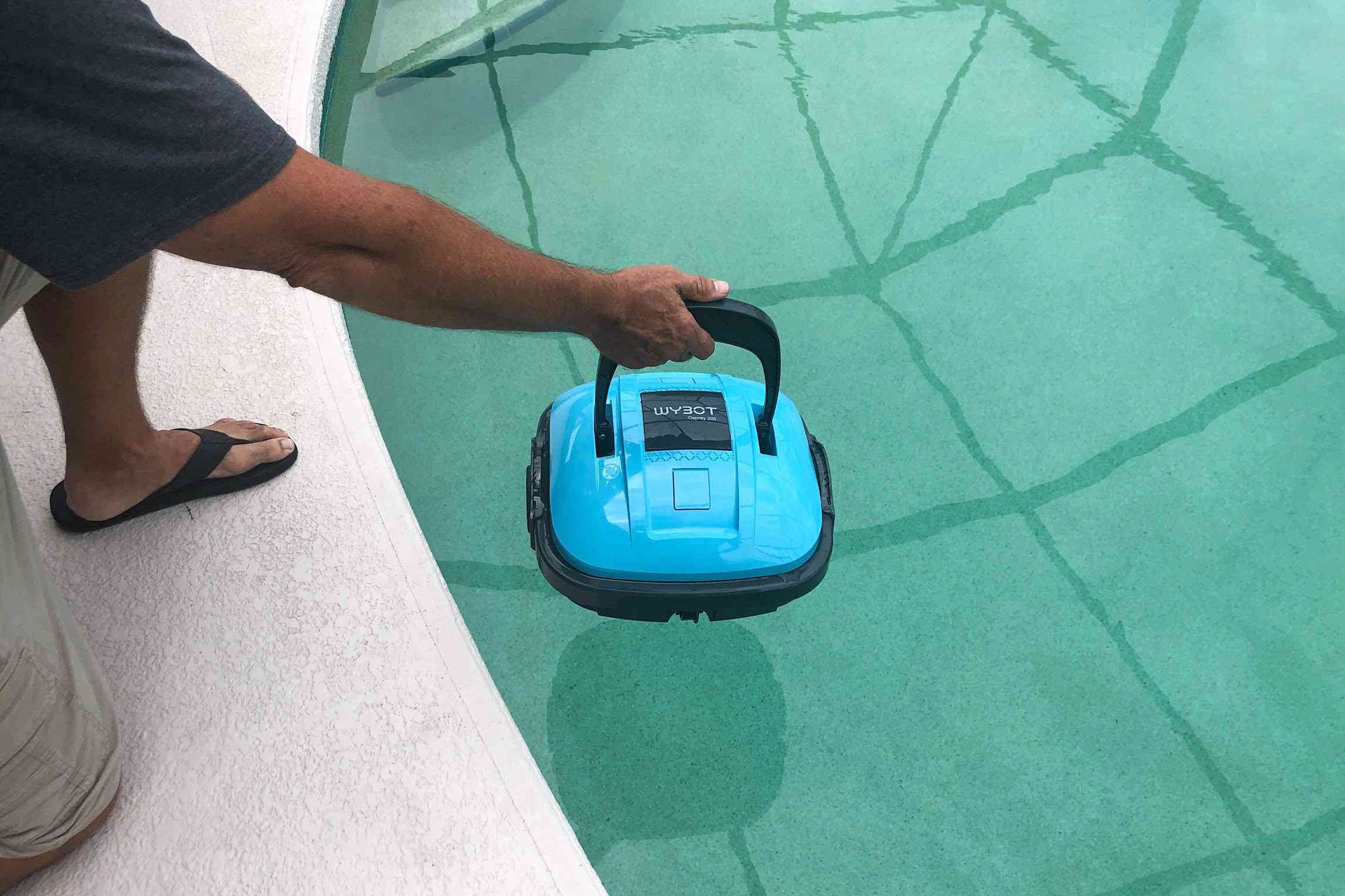 A person places the WYBOT Cordless Robotic Pool Cleaner into a pool